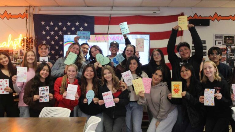 A large group of students holding up letters written for children battling cancer