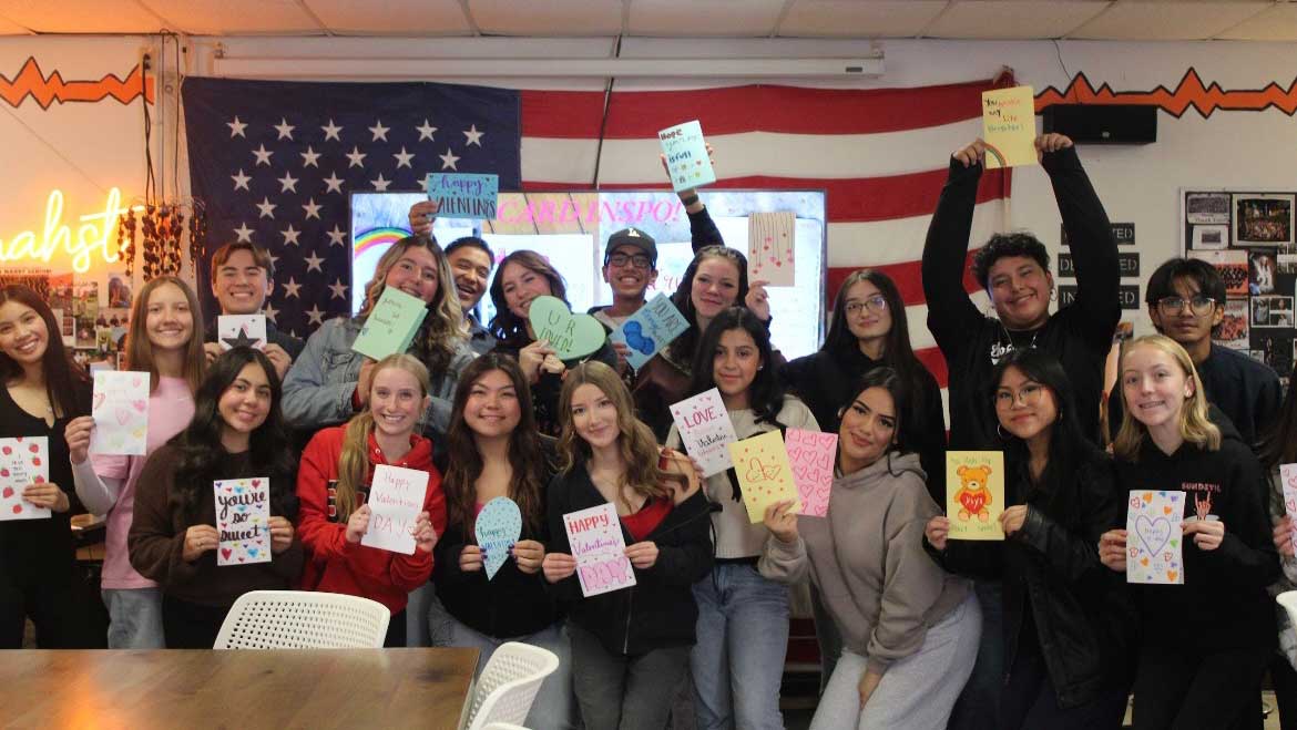 A large group of students holding up letters written for children battling cancer