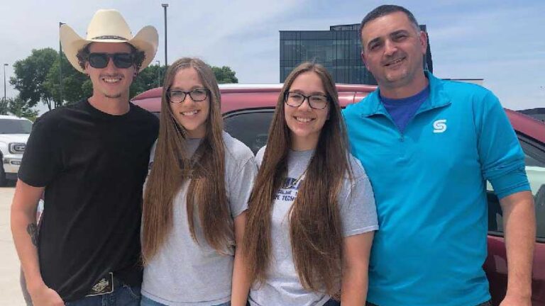 Four people stand together for a photo outside: SkillsUSA advisor Cayden Riley, students Emma and Claire Uhler, and SkillsUSA advisor John Trapletti.