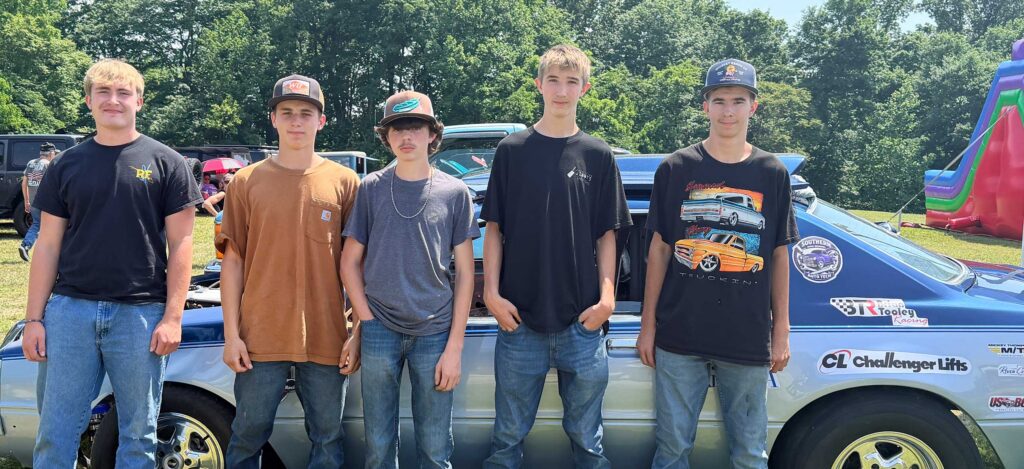 Students pose with a muscle car